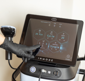Technician adjusting a touchscreen device during body contour clinic and treatments with advanced equipment in a clean treatment room.